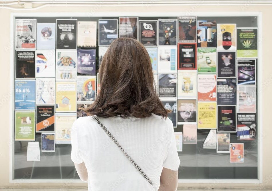 woman looking at wall of designed print materials